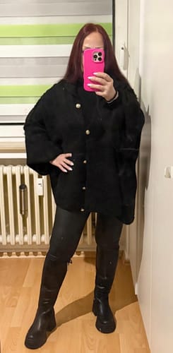 Kundin in dem schwarzen Oversized-Cardigan 'CozyGlam' mit goldenen Knöpfen, gestylt mit schwarzen Leggings.