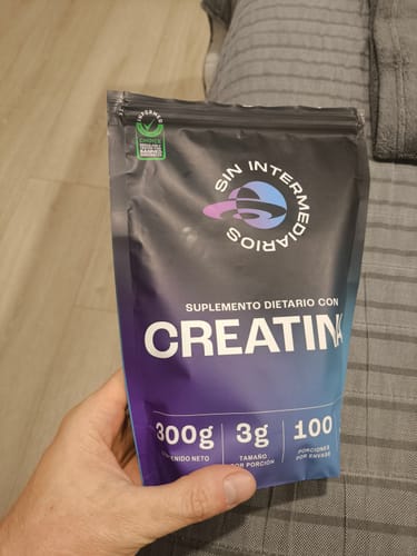 Un cliente sostiene en su mano el empaque negro de 300 g del suplemento Creatina Monohidrato.