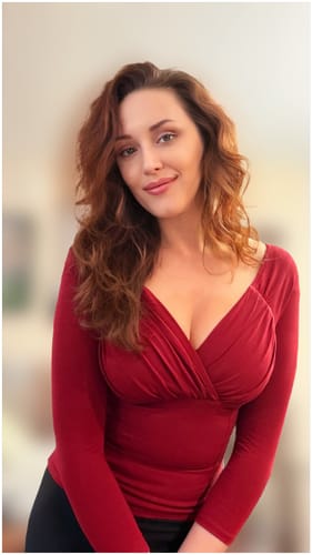 Reviewer showing the fit of the Starlet Top in Ruby Red with its draped V-neck and long sleeves.