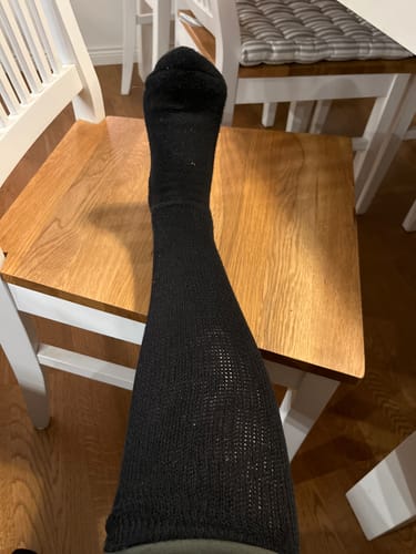 Recensentens ben med en svart Diasocks Komfortstrumpa som visar den lösa passformen upp till knät.