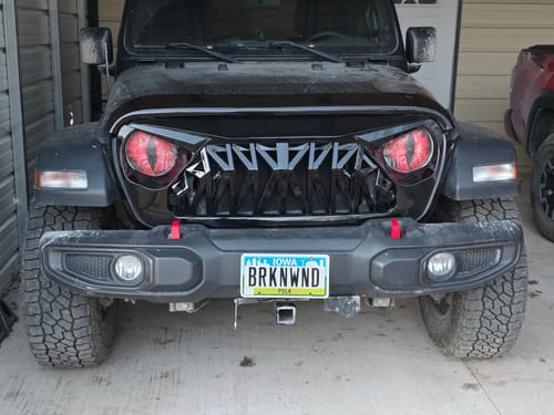 Customer's glossy black Shark Grille installed on the front of a black Jeep, showing its aggressive design.