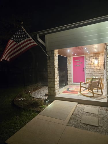 Reviewer's heavy duty American Flag mounted on their home's front porch at night.