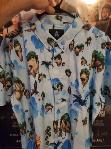 Reviewer holding up their light blue Avatar 'Hallelujah Mountains' shirt, showing the detailed floating islands print.