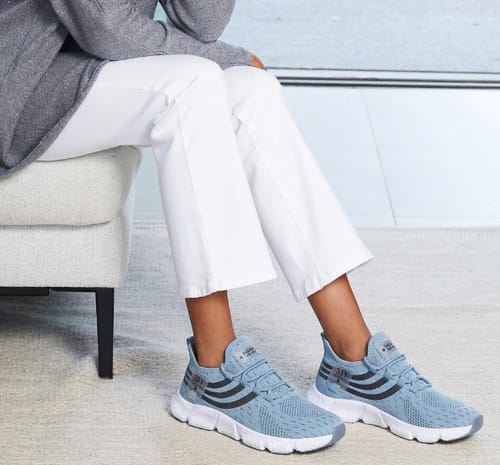 Reviewer sitting and wearing a pair of light blue Easy Step shoes with thick white soles.