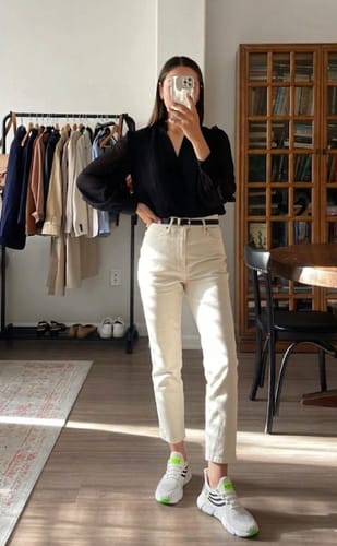 Customer standing indoors wearing white Easy Step shoes with neon green accents and light-colored jeans.