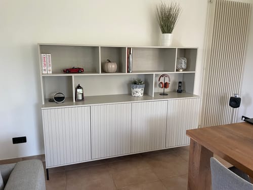 Recensent toont de lichte Gravure wandkast, ingericht met diverse decoratieve spullen in een woonkamer.