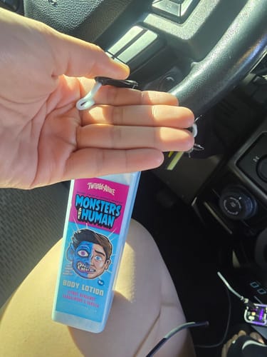 Reviewer holds the Monsters are Human Body Lotion bottle, showing a pump of the white lotion in their hand.
