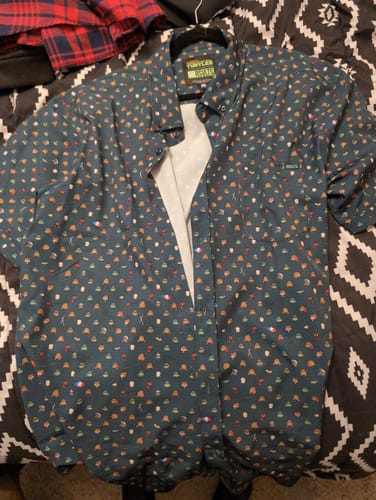 Customer's dark green Teenage Mutant Ninja Turtles shirt laid flat, showing the colorful all-over pattern of characters and icons.