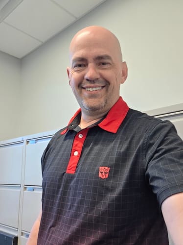 Reviewer smiling while wearing the black 'Team Autobot' polo with a red collar and small red Autobot logo on the chest.