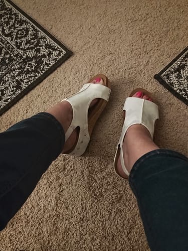 Reviewer's view looking down at their white Corky's Volta II wedge shoes, worn with dark jeans.