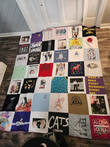 Customer's large T-Shirt Quilt made from many colorful shirts and personal photos, laid out flat on a floor.