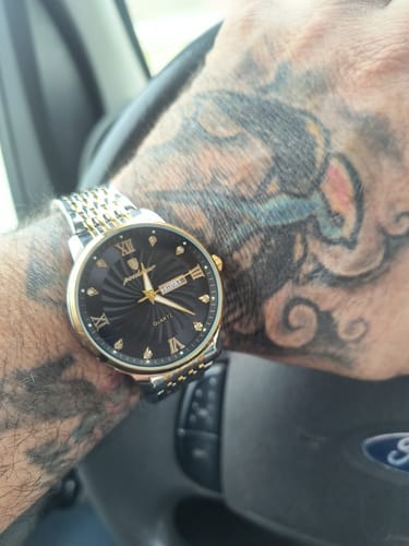 Customer's Lucky Fours® Nassau watch with a black face and two-tone band on their wrist.