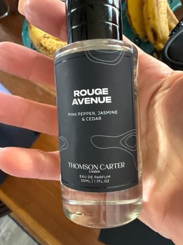 Customer holding a clear bottle of Rouge Avenue Eau de Parfum, showing the black label.