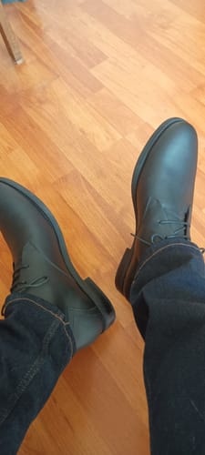Cliente usando los Botines Hombre Texas Negro con jeans oscuros sobre un piso de madera.