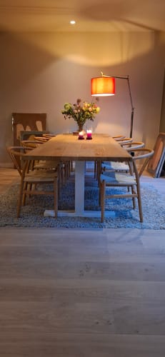 Klantfoto van de by fonQ Brim eetkamerstoelen opgesteld rond een lange houten eettafel.