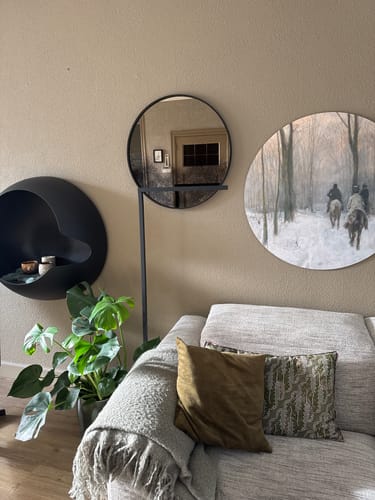 Klantfoto van de zwarte ETH Sem leeslamp geplaatst achter een bank in een gezellige woonkamer.