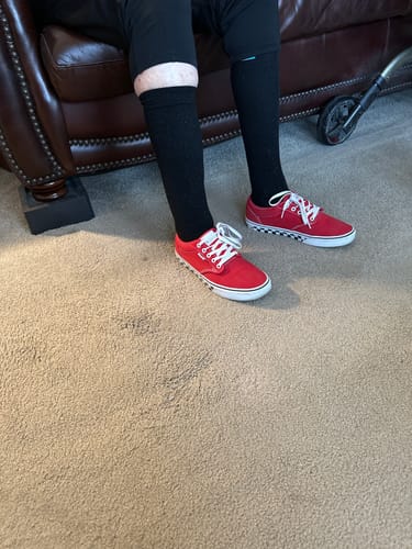 A customer sitting on a couch wearing the black Performance Eucalyptus Compression Socks.