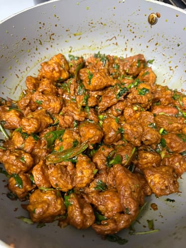 Customer's dish of cooked Halal Veal Cubes in a savory sauce with green herbs.