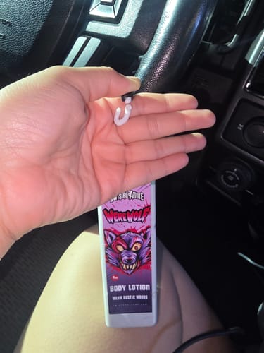 Reviewer holding the Werewolf body lotion bottle in their hand inside a car, showing the werewolf label.