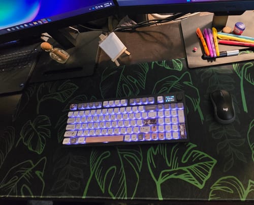 Customer's Tropical Night desk mat with a green leaf pattern shown on a desk with a keyboard and mouse.