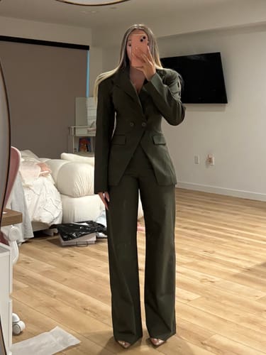 Reviewer in a bedroom trying on the dark green Suiting Tailored Blazer with matching wide-leg pants.