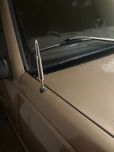 Reviewer's close-up of a silver bullet-shaped antenna installed on a tan truck.