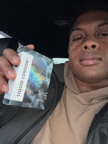 Customer holding the holographic packaging for the For Him Pheromone Perfume in a car.