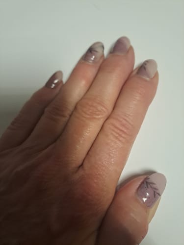 Hand einer Kundin, die die 'Stone Minimalist' UV-Gel-Nagelfolien in einem dezenten Nude-Ton mit Blattdesign trägt.