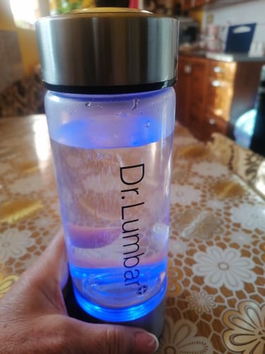 Vásárló kezében tartja a működés közbeni, kék fénnyel világító Hydrofresh hidrogénes víz készítő üveget.