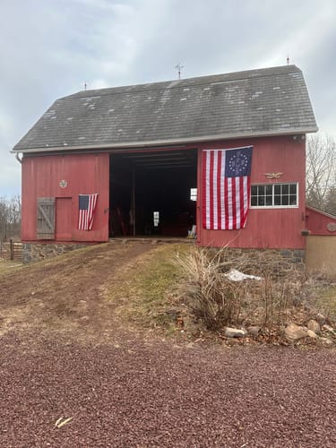 Customer's large Betsy Ross Flag hanging on the side of a rustic red barn.