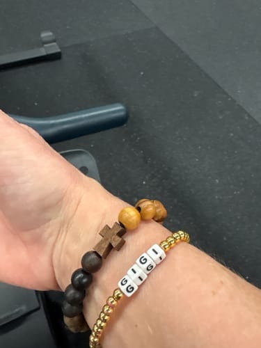Customer's wrist with the Remain With Me Lent Bracelet, showing the wooden beads and cross detail.
