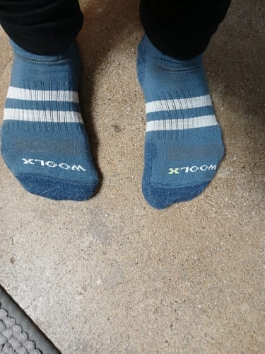 Customer standing in blue Rambler Ankle Socks with white stripes, viewed from above on a concrete floor.