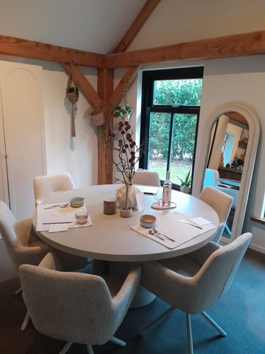 Klant toont de beige by fonQ Weld eetkamerstoelen rond een ronde eettafel in een sfeervolle eetkamer.