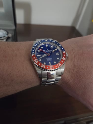 Customer wearing their Oceaneva GMT watch, showing the blue dial and the red and blue bezel on their wrist.