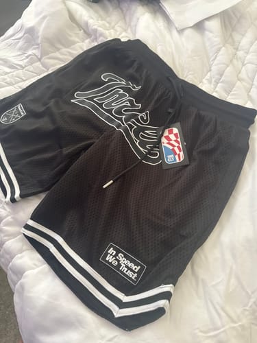 Customer's new ISWT HARDWOOD BALLER SHORTS in black, laid out on a white comforter to show the heavyweight mesh quality and logos.