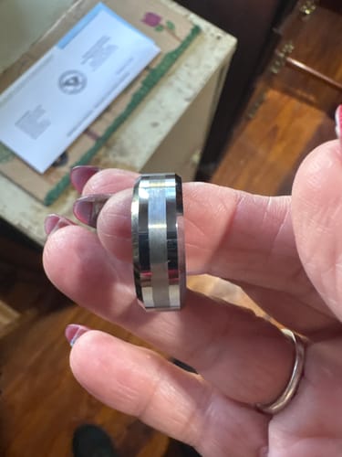 Customer holding the Alaric ring, showing its brushed-satin center and polished beveled edges.