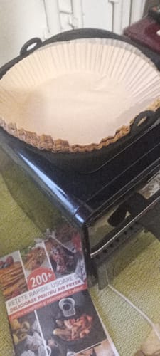 Recenzent arătând un teanc de hârtii de copt rotunde în coșul unei friteuze.