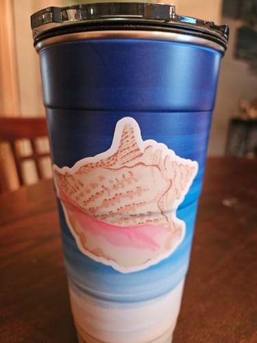 Customer's Tan Seashell Sticker applied to a blue and white ombre travel cup.
