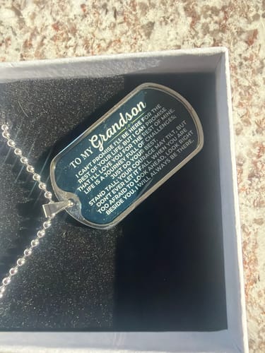 Close-up of reviewer's stainless steel 'To My Grandson' love tag in its gift box, showing the printed message.