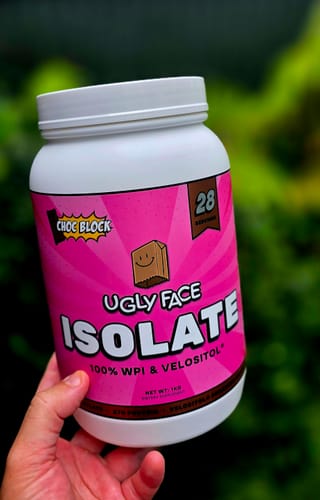 Reviewer holding the bright pink tub of Choc Block UGLYFACE ISOLATE protein.