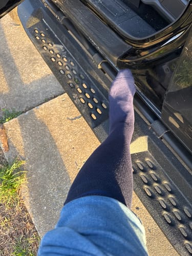 Customer's leg wearing a dark Performance Eucalyptus Compression Sock while stepping out of a vehicle.