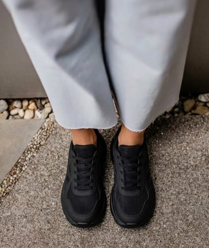 Customer standing on pavement, providing a top-down view of their all-black Motion X shoes.