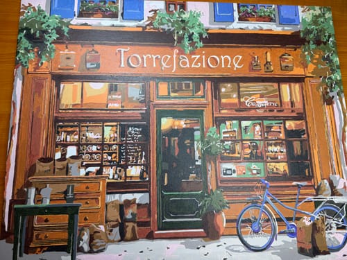 Reviewer's completed, colorful paint-by-numbers canvas of a shop storefront, made with the extra paint kit.