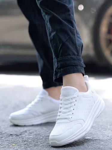 A reviewer wearing the all-white Balance Pro shoes while standing on an asphalt road.