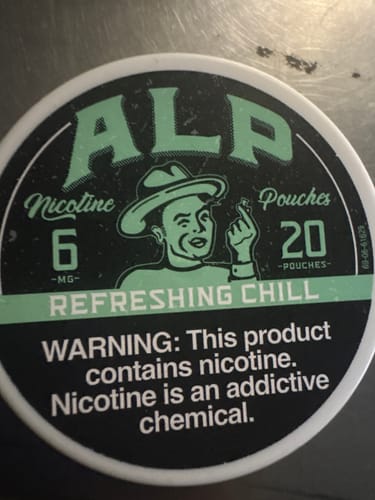 Close-up of a customer's tin of ALP Refreshing Chill Nicotine Pouches on a surface.