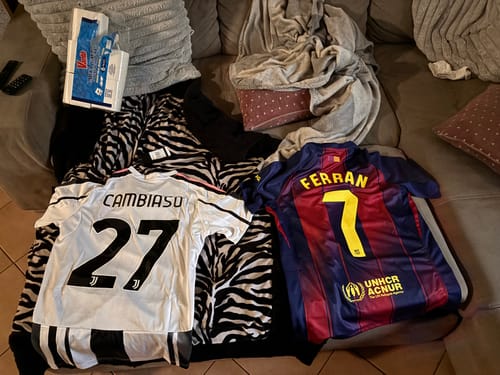 Cliente mostra la maglia della Juventus Home personalizzata 'CAMBIASO 27' stesa su un divano accanto a un'altra maglia.