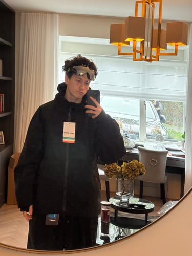 Reviewer trying on the oversized black snow jacket in a mirror selfie.