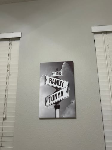 Customer's personalized street sign canvas with the names Randy and Tonya and the year 1999, hanging on a wall.