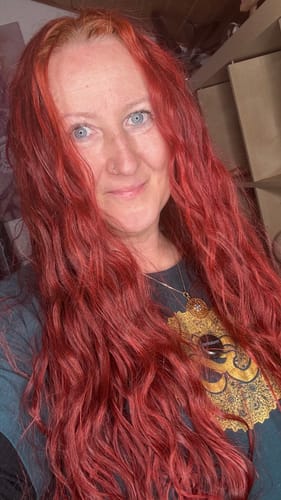 Eine Kundin zeigt ihr langes, weiches Haar mit Wellen nach der Anwendung der Ylang-Ylang-Glow Haarseife.