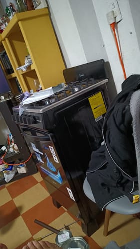 Un cliente muestra su estufa de piso Midea MasterCook negra recién instalada en un espacio de su casa.